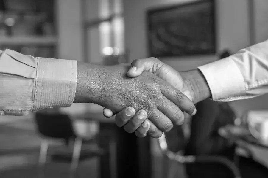 Two people shaking hands, representing the trust at the core of AI native product design.