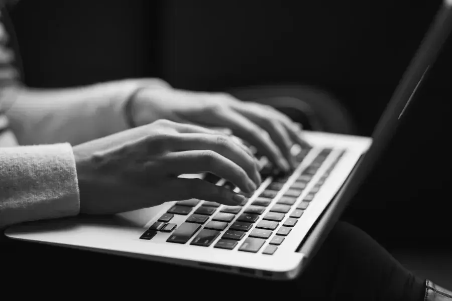 Hands typing on a laptop, writing and refining an AI agent’s prompt.